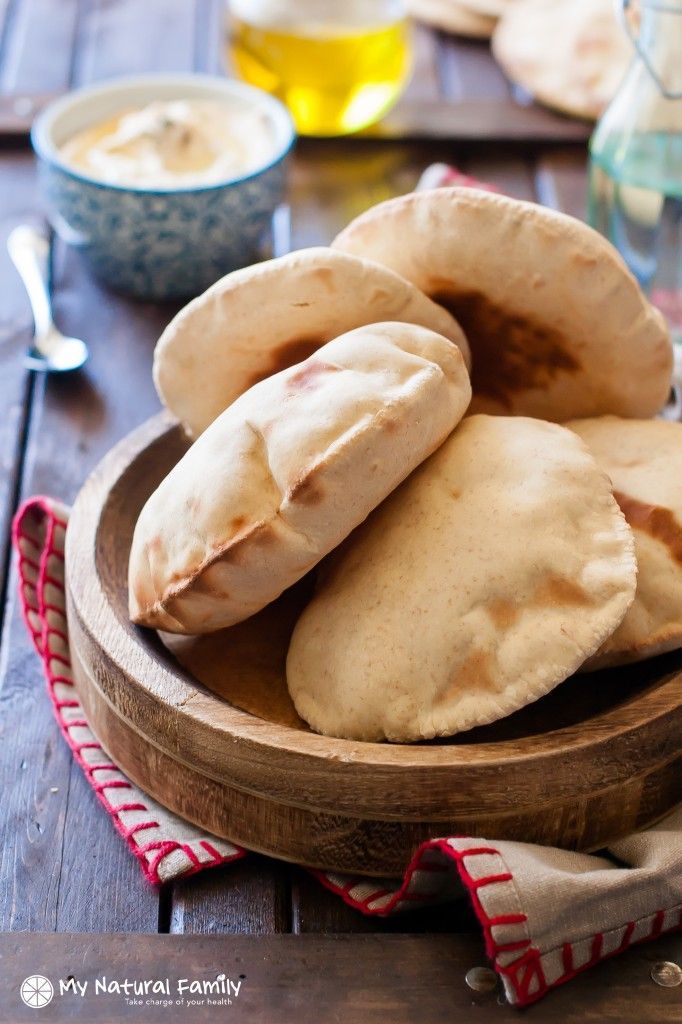 several pita breads in a wooden bowl on a table