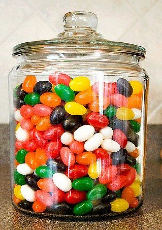 a glass jar filled with lots of colorful candies on top of a countertop