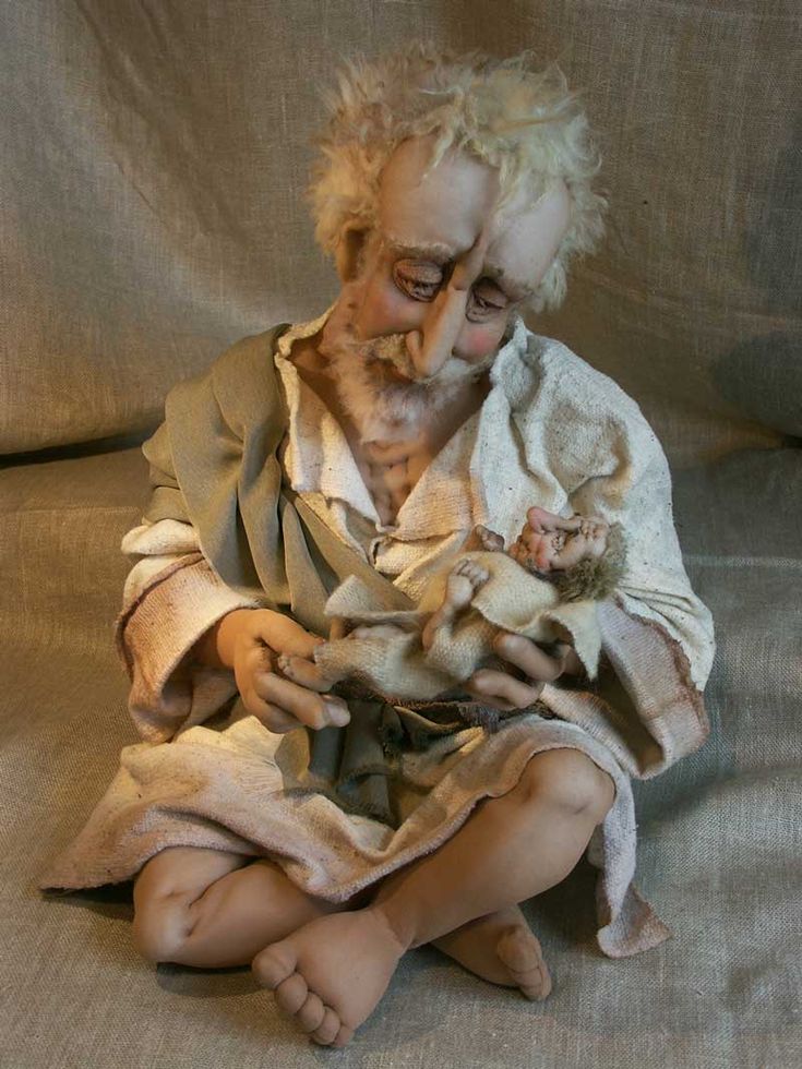 an old man with white hair sitting on a couch holding a stuffed animal in his hands