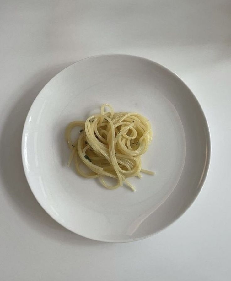 a white plate topped with pasta on top of a table