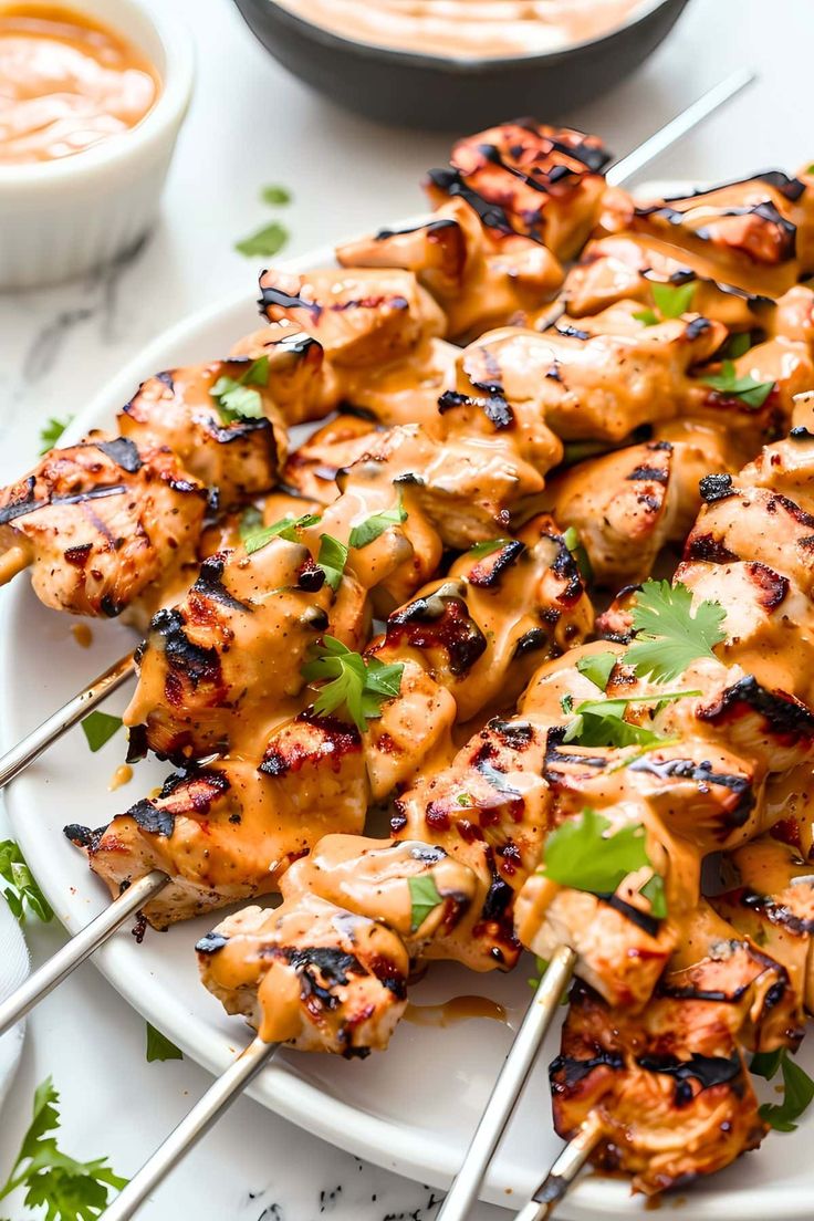 chicken skewers on a plate with dipping sauce