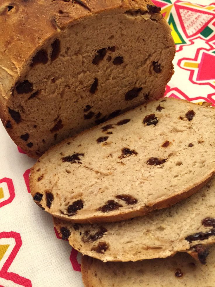 a loaf of bread with raisins sitting on top of a colorful table cloth