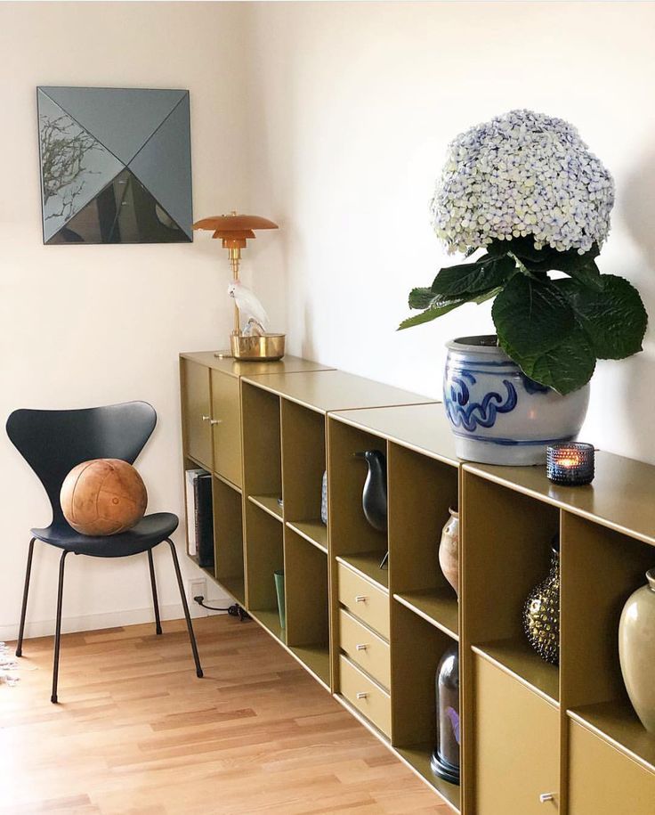 a vase with flowers is on top of a shelf next to a chair and other items