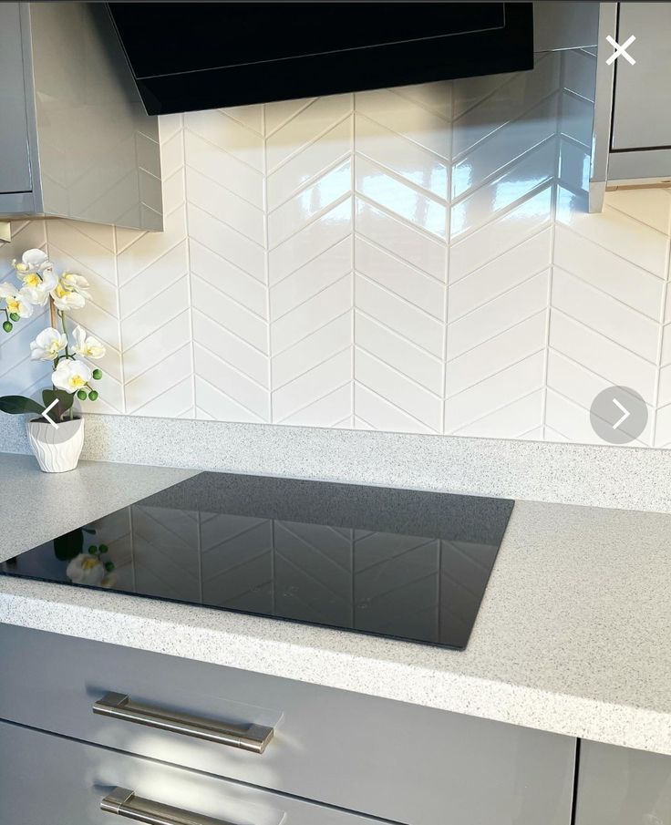 a kitchen counter with flowers in a vase on it and white tile backsplash