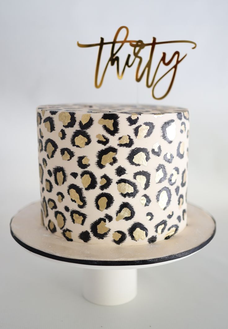 a leopard print cake with the word thirty on top and gold foiled letters above it