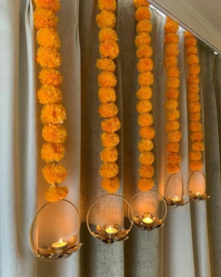 orange flowers are hanging from the side of a curtain with candles in front of them