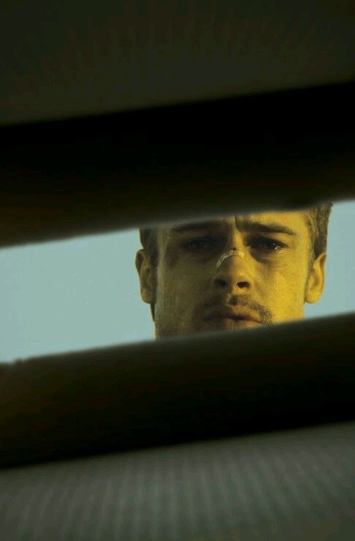 the man is looking out from behind bars in his car window as he stares into the distance