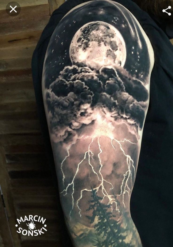 a man's arm with a full moon and clouds on it