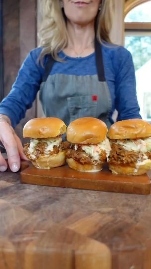 a woman standing in front of three hamburgers