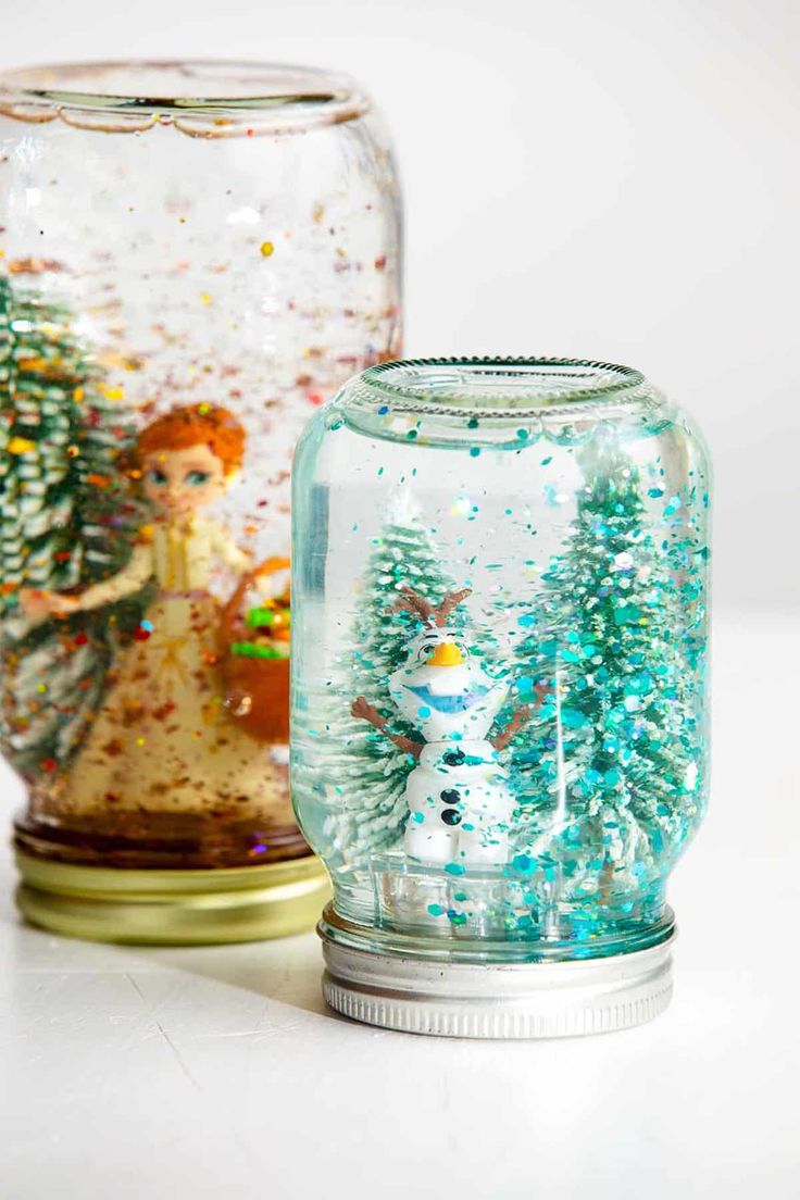 two snow globes sitting next to each other on top of a white countertop