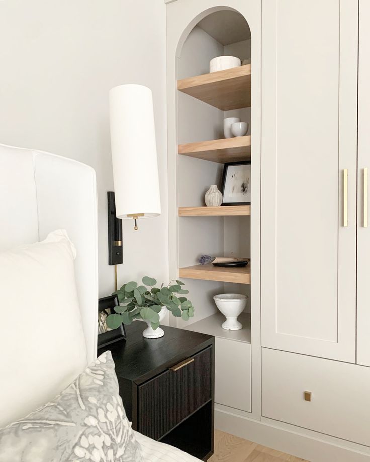 a white bed sitting next to a book shelf