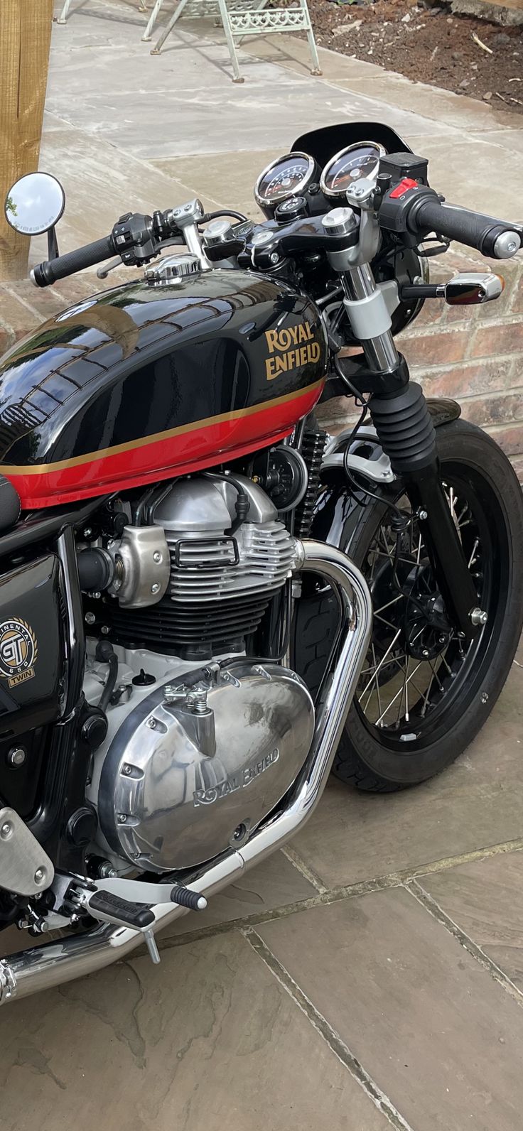 a black and red motorcycle parked on top of a stone floor next to a brick wall