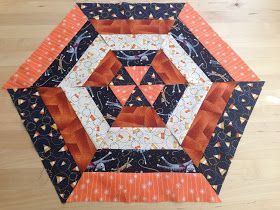 an orange and black patchwork quilt on a wooden floor with the center piece cut out