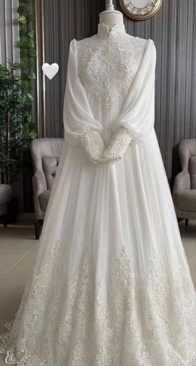 a white wedding dress with long sleeves and laces on the skirt is displayed in front of a mirror