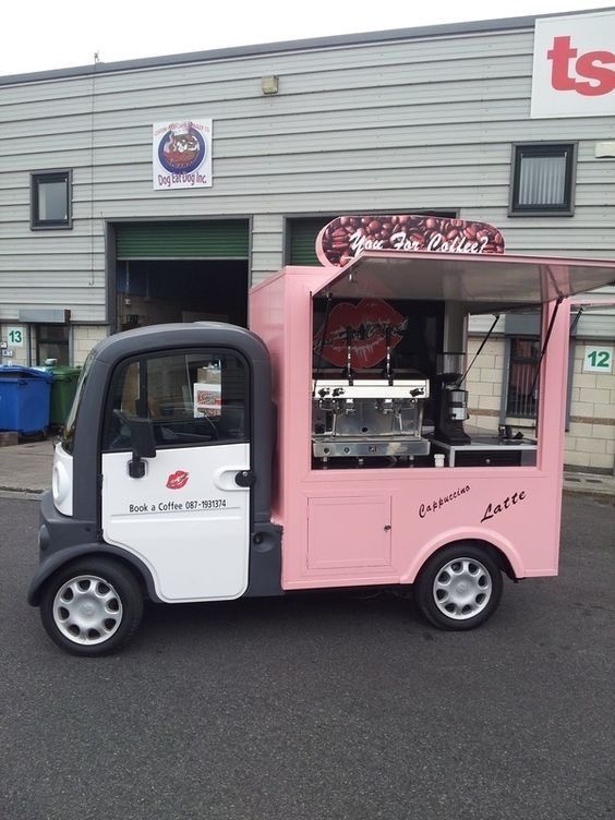 a pink and white food truck parked in front of a building with a sign on it