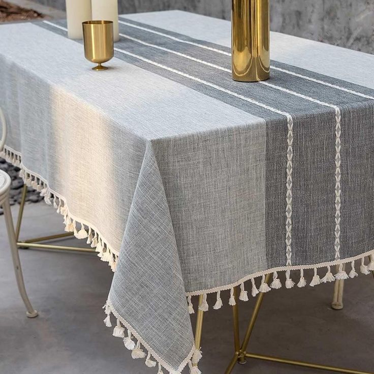 a table with two candles on it and a white table cloth draped over the table