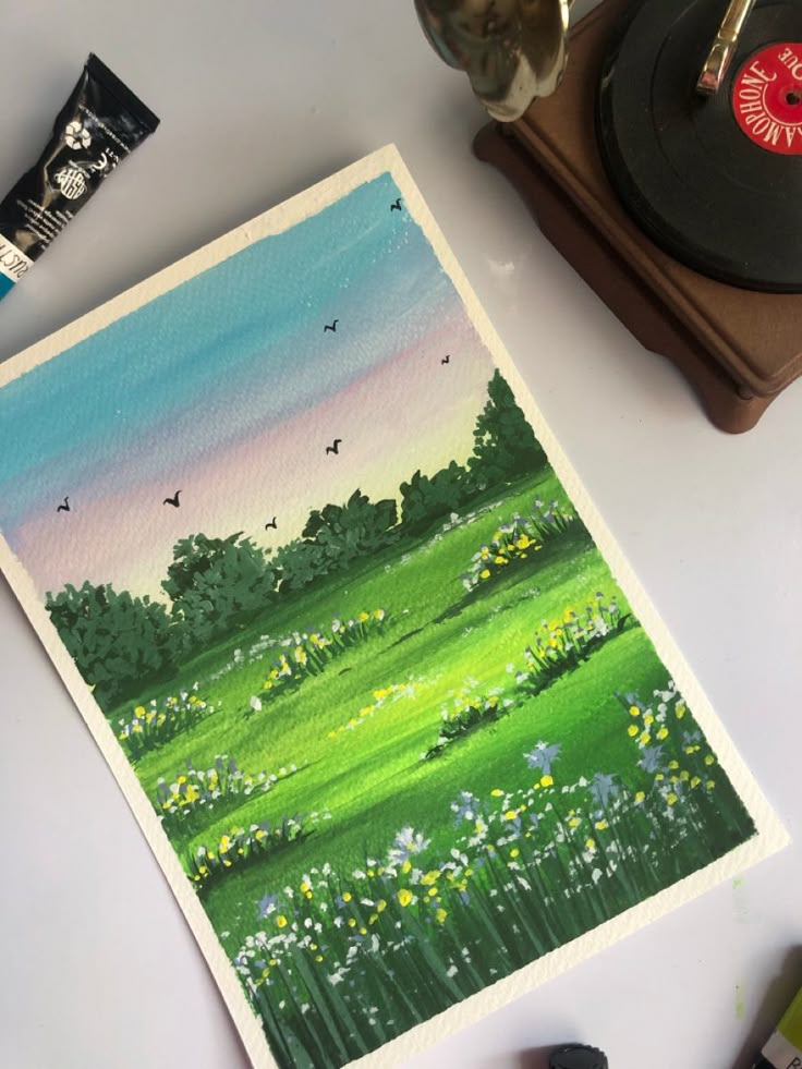 a painting of a green field with flowers and birds in the sky next to a record player