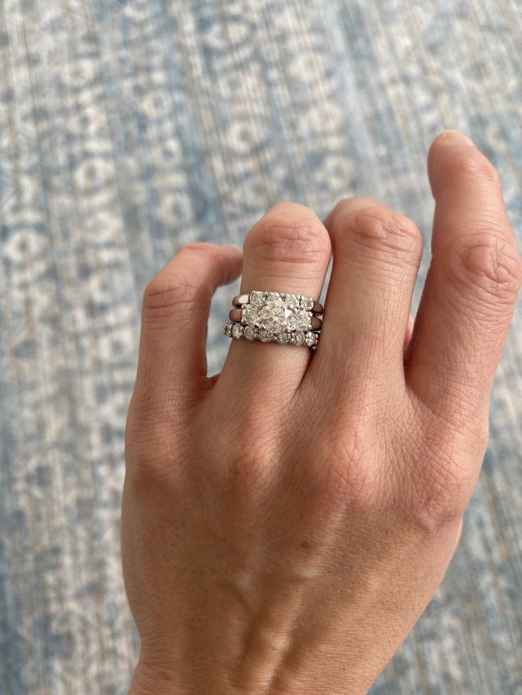 a woman's hand with a wedding ring on her left hand and an engagement band on her right