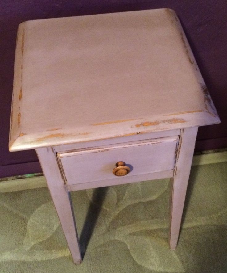 an old white table with a drawer on it's side and a purple wall in the background