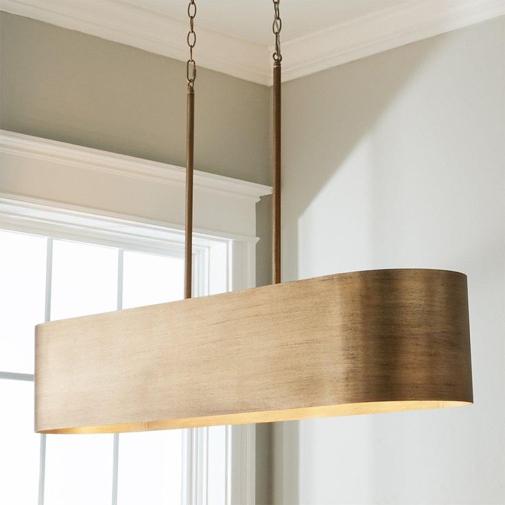 a wooden light fixture hanging from a ceiling in a room with white walls and windows