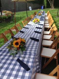 a long table is set up with blue and white checkered cloths for an outdoor event