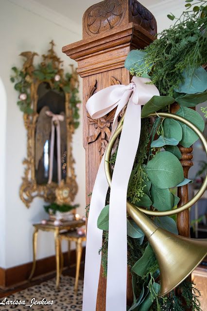 a christmas wreath with bells and greenery on the front of a wooden clock tower