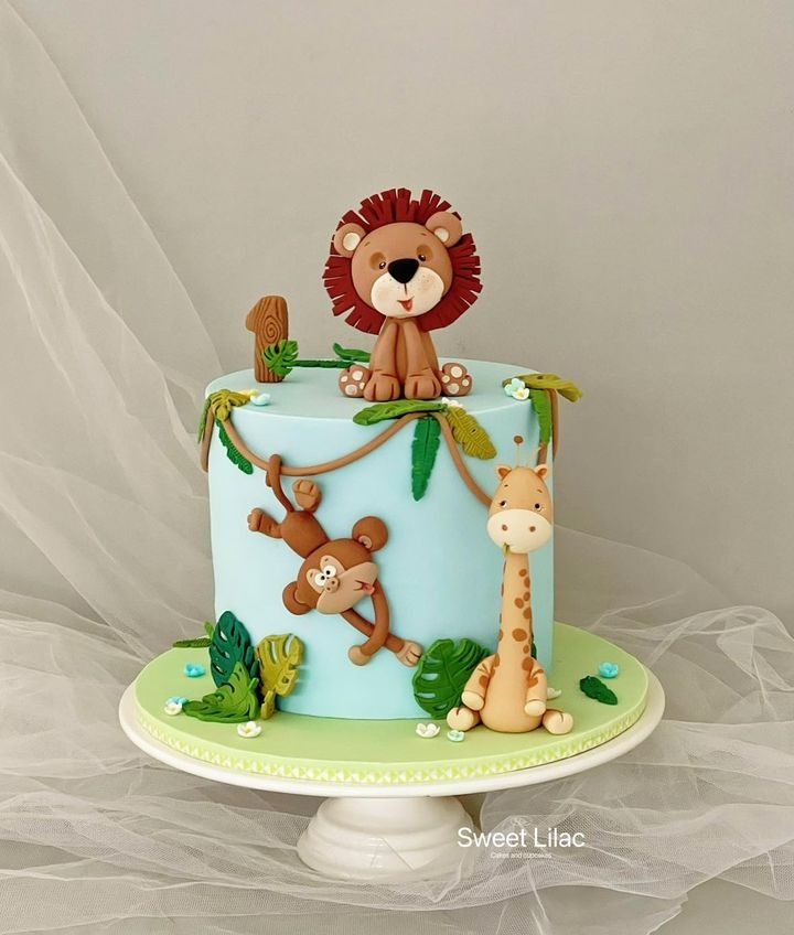 a blue and green cake decorated with monkeys, giraffes and a lion