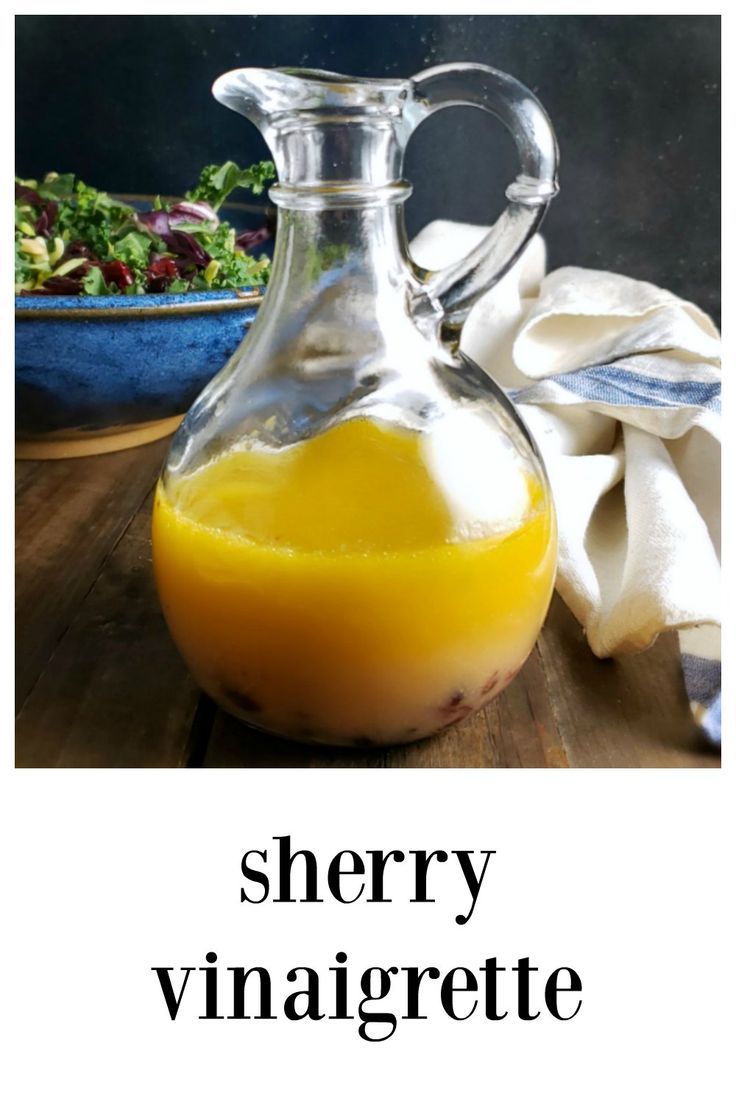 a glass pitcher filled with orange juice next to a bowl of salad