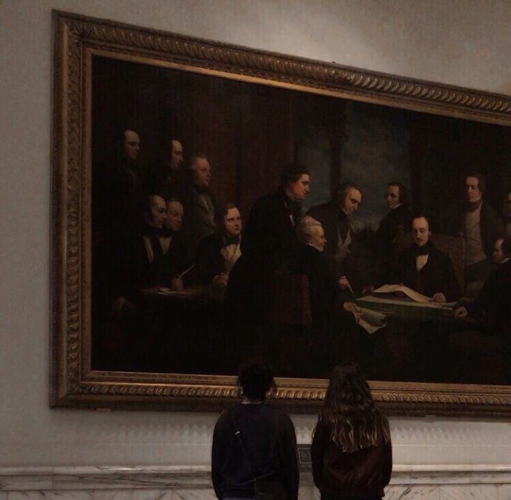 two people standing in front of a large painting