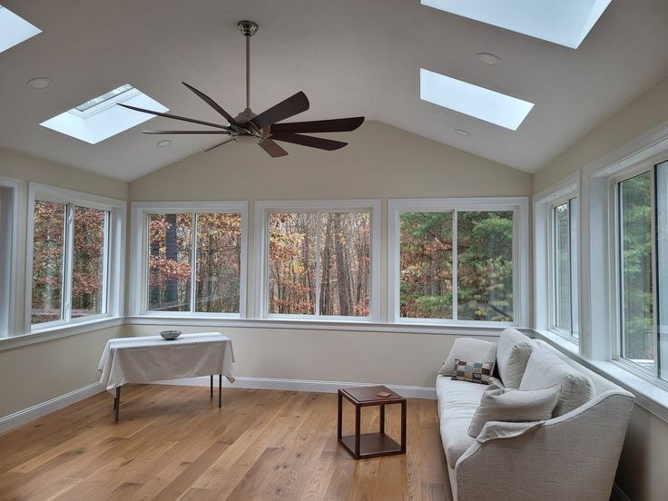 a living room filled with furniture and windows covered in skylights, next to a white couch