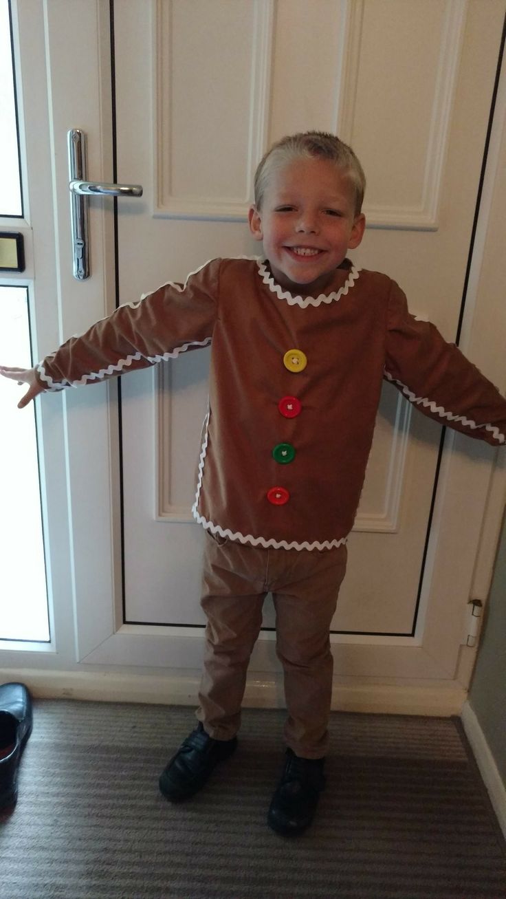 a little boy dressed up like a ginger standing in front of a door with his arms out