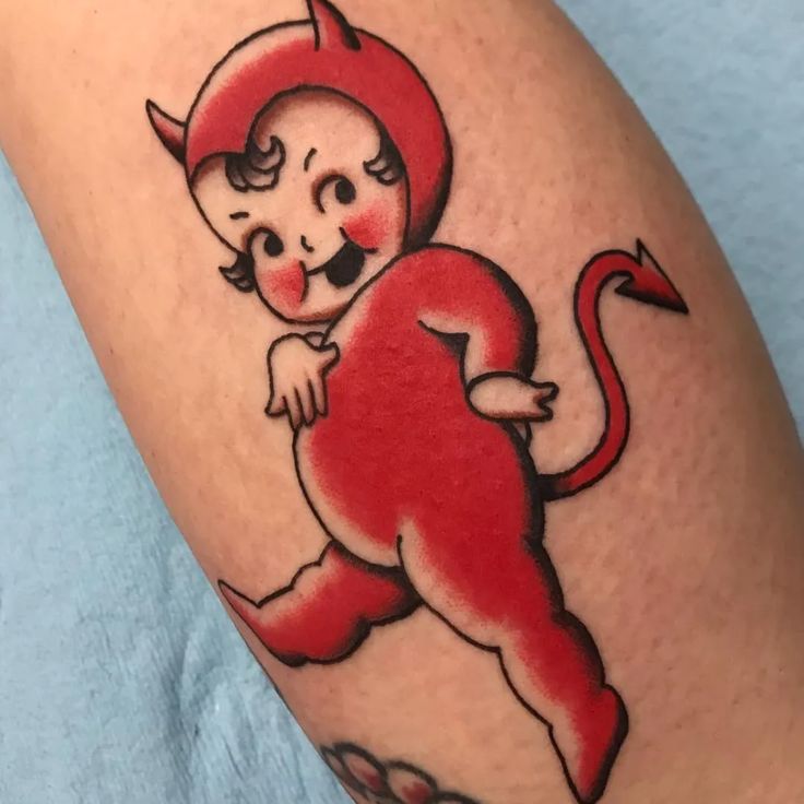 a small red devil tattoo on the leg