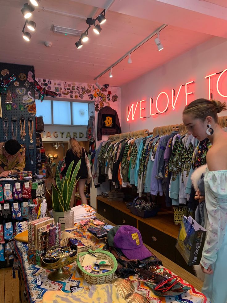 a woman standing in front of a clothing store with lots of items on the counter