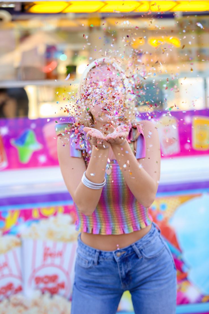 a woman standing in front of a carnival machine with confetti all over her face