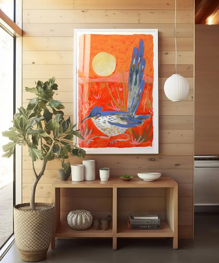 a painting hangs on the wall next to a potted plant