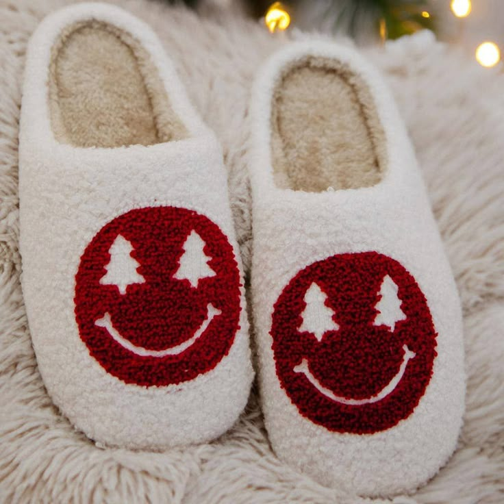 a pair of white slippers with trees and smiling faces on them sitting on a furry surface