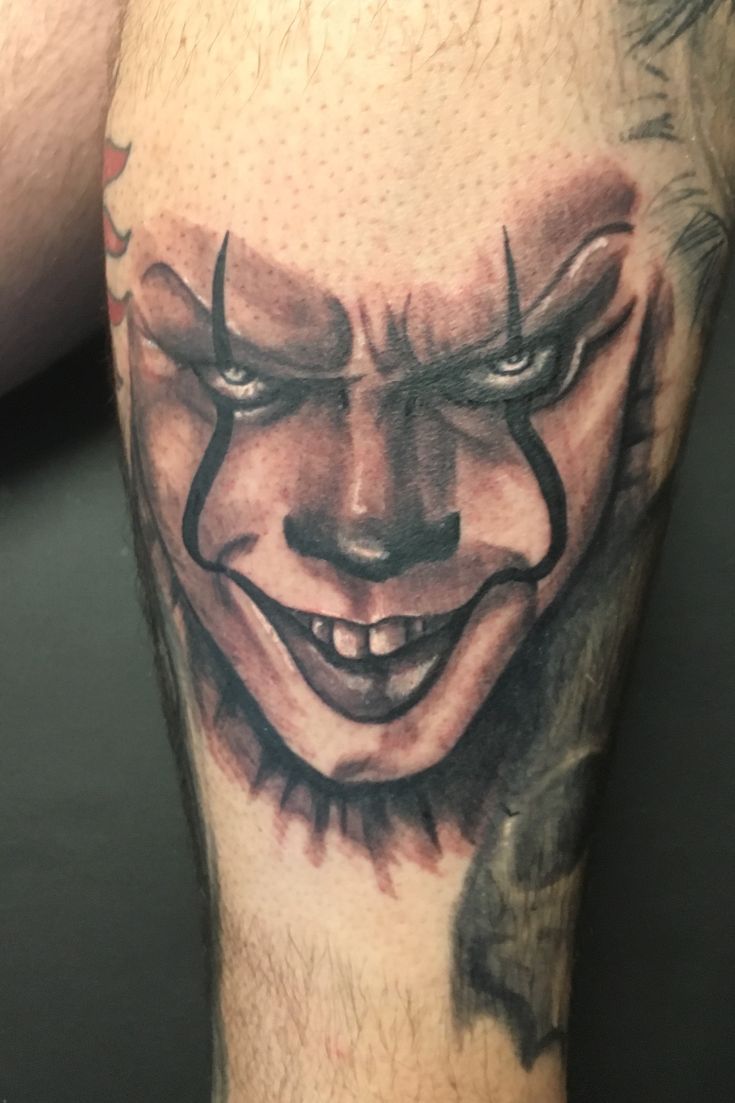 a close up of a person's leg with a clown face tattoo on it