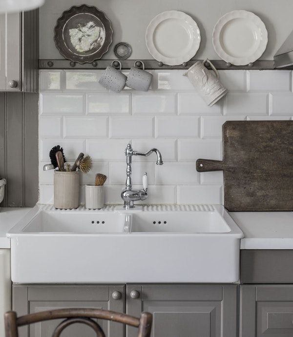 a white kitchen sink sitting next to a counter top with plates and utensils on it