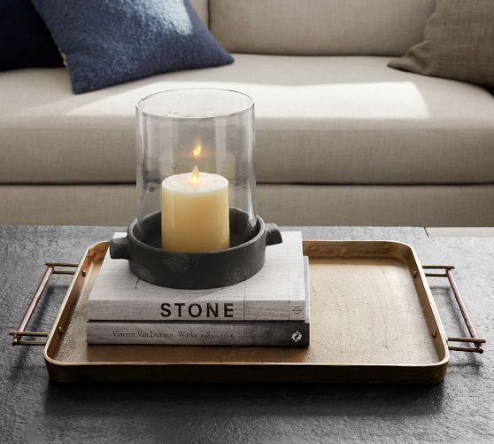 a tray with a candle on top of some books and a couch in the background