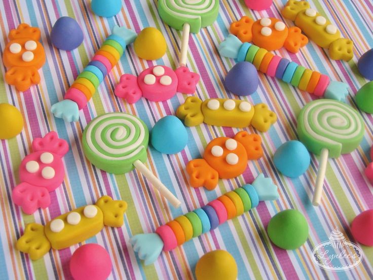 colorful candies and lollipops are arranged on a striped tablecloth,