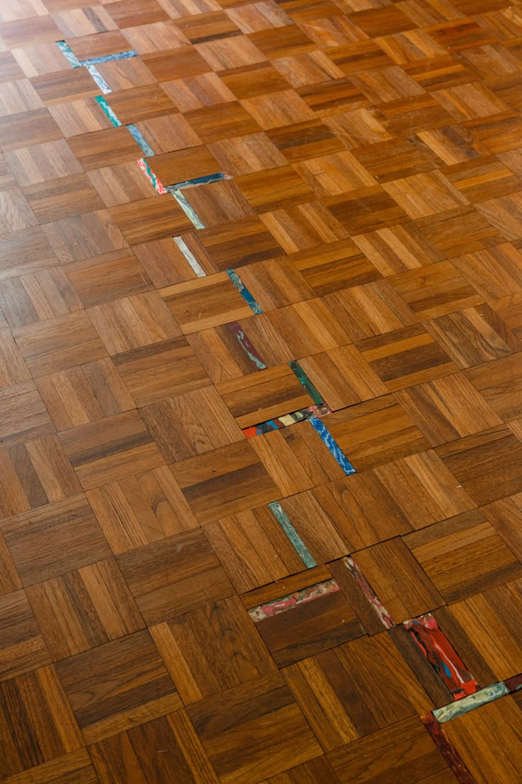 the floor is made up of wood and has strips of tape taped to it with scissors