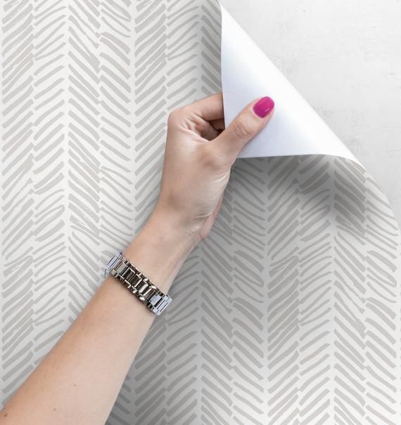 a woman's hand holding an origami piece of paper over a wall