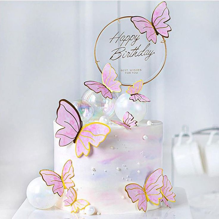 a white cake with pink butterflies on it's top and the words happy birthday written in spanish