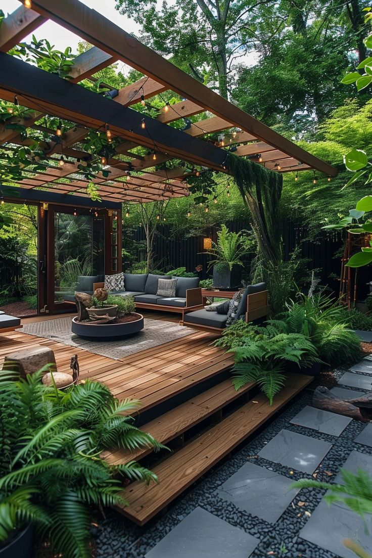 Chic backyard oasis featuring wooden decking, cozy seating, hanging lights, and lush greenery, perfect for outdoor living and backyard landscaping ideas. Backyard Patio Oasis Ideas, Big Backyard Design Layout, Backyard Design Layout On A Budget, Private Master Patio, Backyard Landscaping Full Sun, Backyard Pagoda Patio Ideas, Garden And Patio Ideas, Small Backyard With Deck Ideas, Front Yard Patio Designs