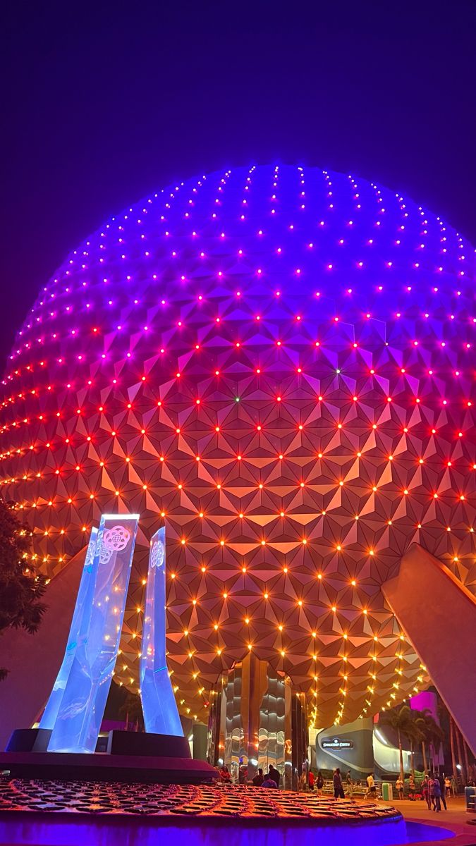 the spaceship shaped building is lit up at night with colorful lights on it's side