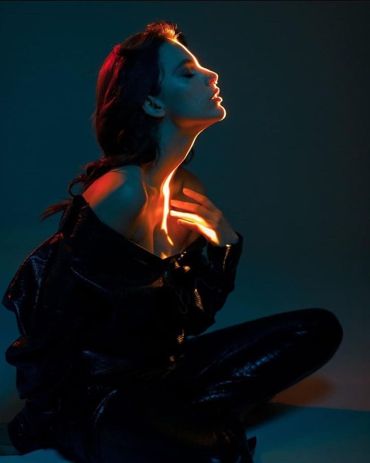 a woman is sitting on the floor with her head turned to the side and glowing