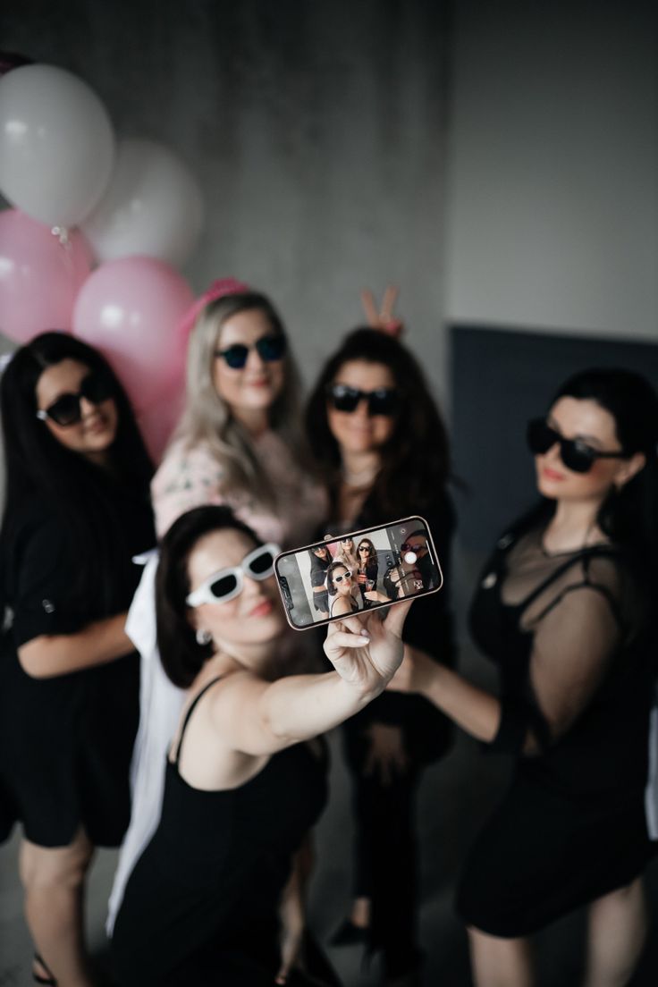 a group of women taking a selfie with their cell phone in front of them