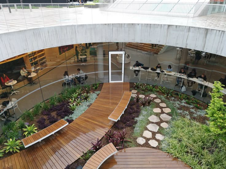 the inside of a building with people sitting at tables and plants on the outside wall