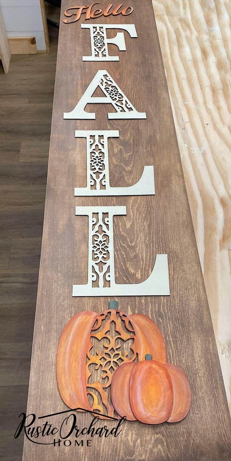 a wooden sign that says fall and pumpkins are on the side of a table