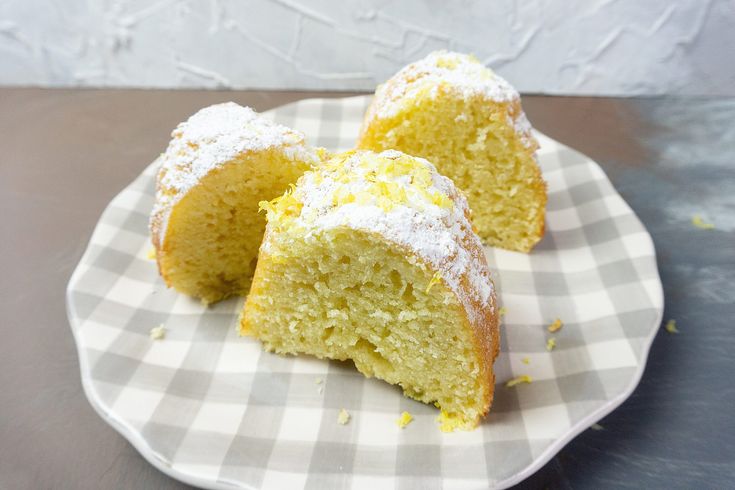 three pieces of cake sitting on top of a white and gray plate with gingham cloth